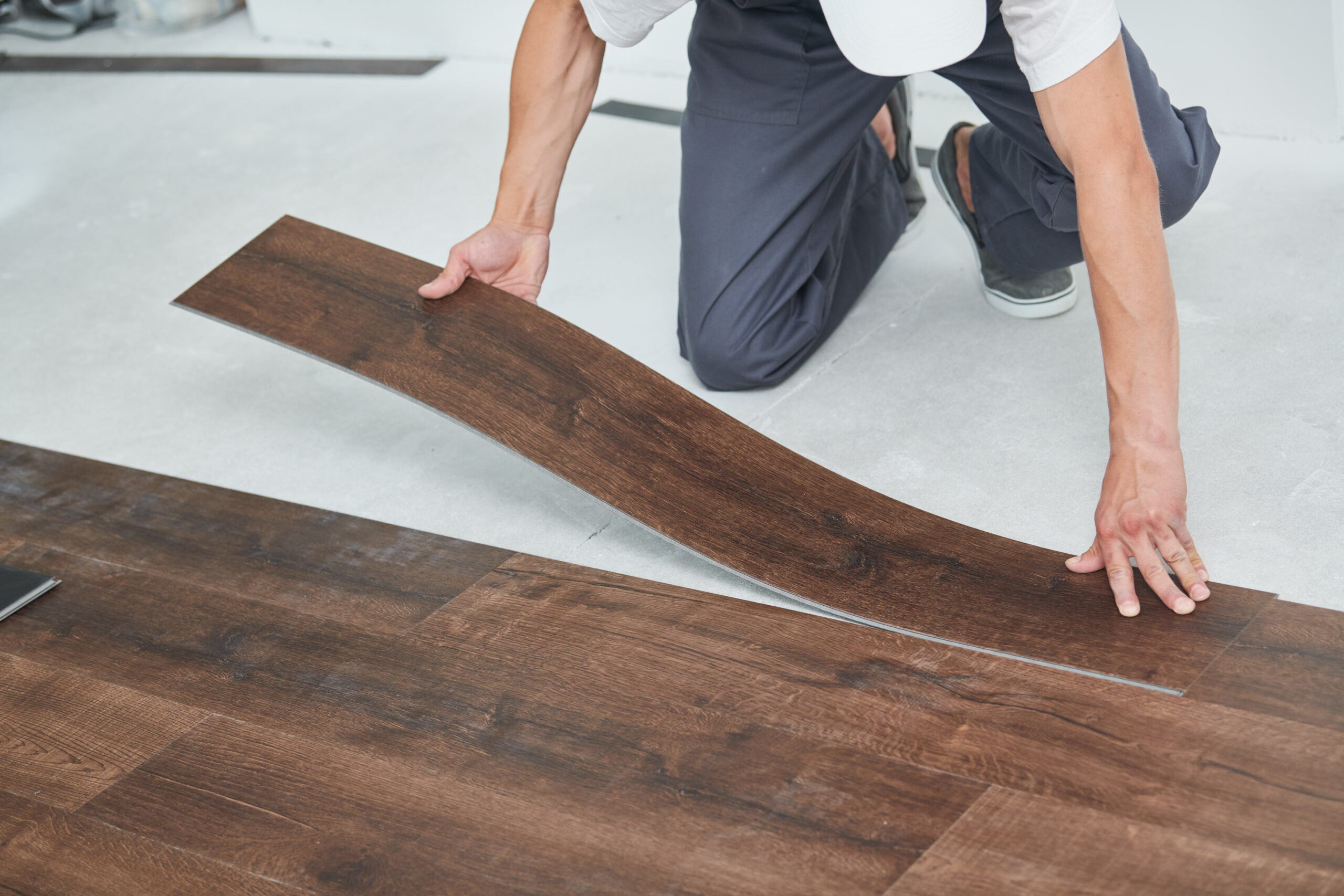 indoor floor installation. carpenter worker installing vinyl floor tiles with wood decoration,